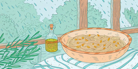 A bowl of THC olive oil pasta next to the bottle of infused oil used in the recipe.